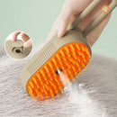 Pet grooming brush with orange bristles being used on a surface, with a close-up inset showing the brush head.
