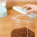 Hand opening a clear jar with pet food on a wooden surface