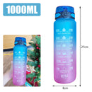 Blue and purple motivational water bottle with time markers and a Christmas tree in the background